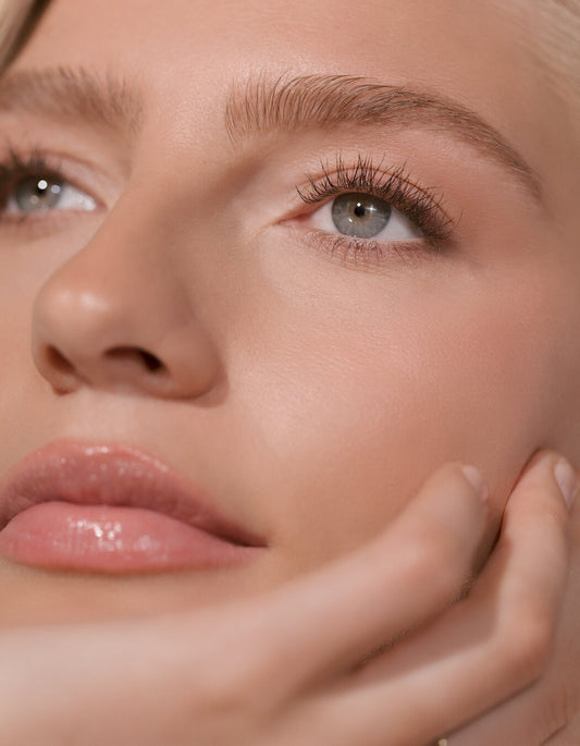 Nahaufnahme des Gesichts einer Frau mit reiner Haut und natürlichem Make-up und geformten Augenbrauen.