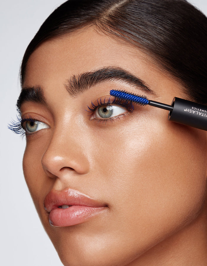 Eine Frau trägt mit einer Bürste blaue Wimperntusche des Double-Ended Volume Mascara Set auf ihre oberen Wimpern.