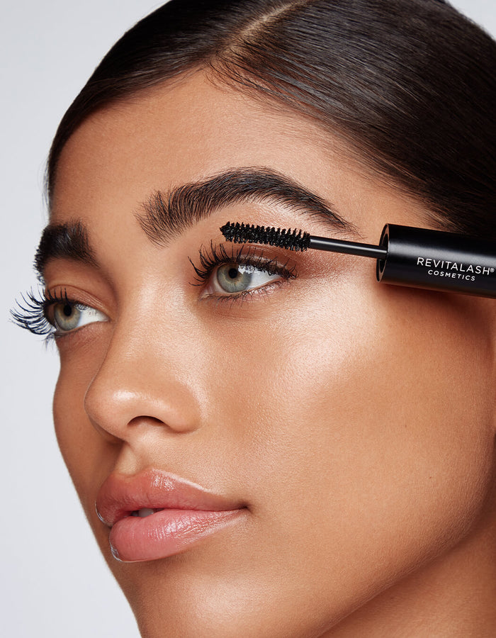 Eine Frau trägt mit einer Bürste schwarze Wimperntusche des Double-Ended Volume Mascara Set auf ihre oberen Wimpern.