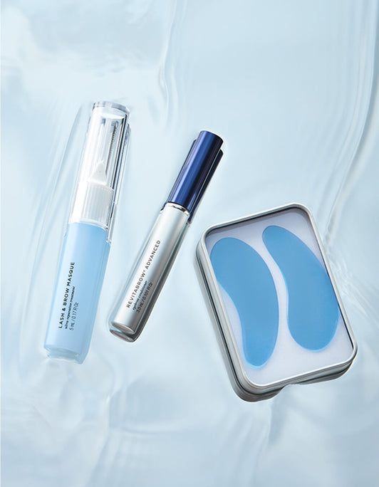 Drei Pflegeprodukte der RevitaLash® Cosmetics Brow Refresh Collection, darunter RevitaBrow Advanced Spring 2025 auf Wasseroberfläche: Lash & Brow Masque, RevitaBrow-Serum und blaue Augenpads in Metallbox.