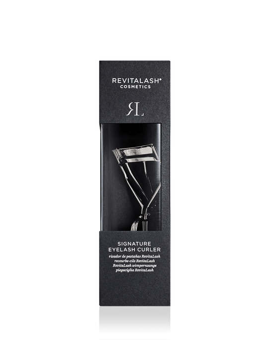 Schwarze Boxverpackung des RevitaLash® Cosmetics Signature Eyelash Curler mit Plastikfenster legt sicht auf silberne Wimpernzange frei.