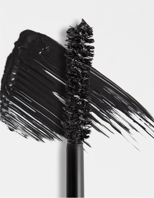 Nahaufnahme des schwarzen RevitaLash® Cosmetics Double-Ended Volume Mascara Set Mascarabürstchens mit einem Hauch schwarzer Mascara auf weißem Hintergrund.