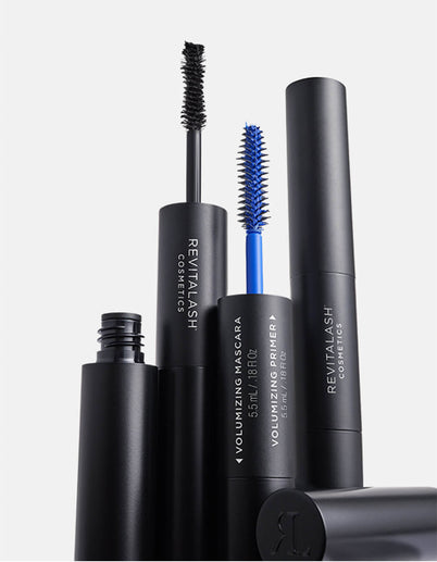 Mehrere schwarze Tuben des Double-Ended Volume Mascara Set von RevitaLash mit schwarzen und blauen Mascara-Bürstchen auf einem weißen Hintergrund.