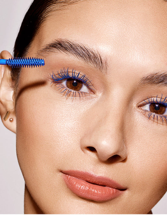 Eine Frau trägt die blaue Mascara des Double-Ended Volume Mascara Set von RevitaLash® Cosmetics auf ihre Wimpern auf und betont so ihr Augen-Make-up.