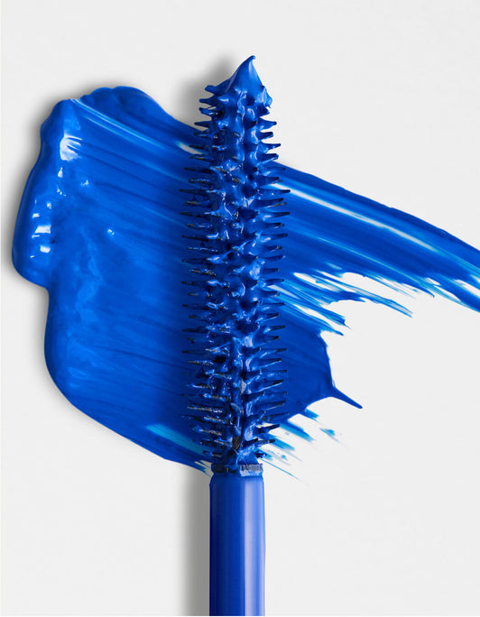 Nahaufnahme des blauen RevitaLash® Cosmetics Double-Ended Volume Mascara Set Mascarabürstchens mit einem Hauch blau leuchtender Mascara auf weißem Hintergrund.
