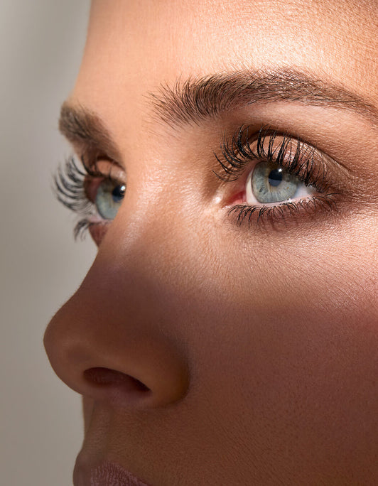 Nahaufnahme von blauen Augen mit langen, geschwungenen Wimpern und gepflegten, definierten Brauen im natürlichen Look.