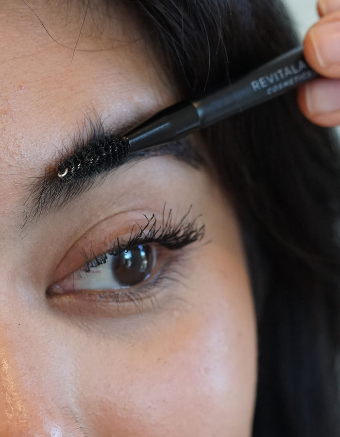 Eine Nahaufnahme einer Person, die ihre Augenbrauen mit dem RevitaLash® Cosmetics Lash & Brow Styler bürstet.
