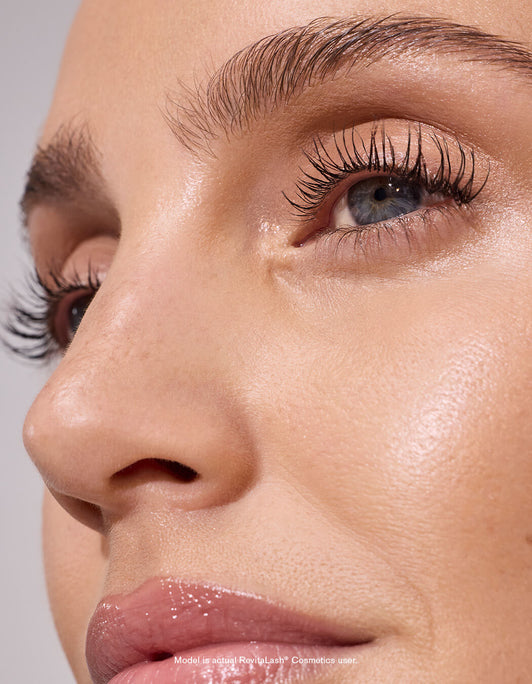 Nahaufnahme eines Frauengesichts mit glänzenden Lippen, strahlender Haut und langen Wimpern, die durch RevitaLash® Cosmetics Spotlight on Lashes RevitaLash® Advanced Spring Collection 2026 verschönert werden.
