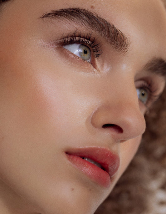 Eine Nahaufnahme des Gesichts einer Person mit klarer Haut, grünen Augen, vollen Brauen und Focus auf langen geschwungenen Wimpern durch RevitaLash® Advanced Sensitive von RevitaLash® Cosmetics.