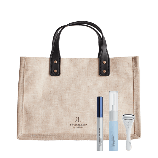 Die Ultimate Brow Collection - RevitaBrow® Advanced Summer 2024 bestehend aus beiger Tasche mit schwarzen Henkeln, der blauen Tube Lash & Brow Masque, einem weißen Eyeroller mit Edelstahlrolle und der silber-blauen Tube RevitaBrow Advanced.