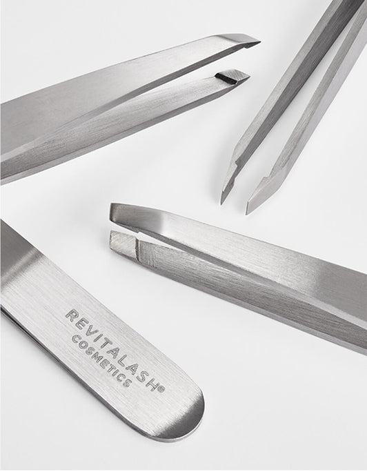 Vier Precision Tweezer Pinzetten von RevitaLash® Cosmetics mit schrägen und Enden, jede mit dem Logo von RevitaLash® Cosmetics versehen.