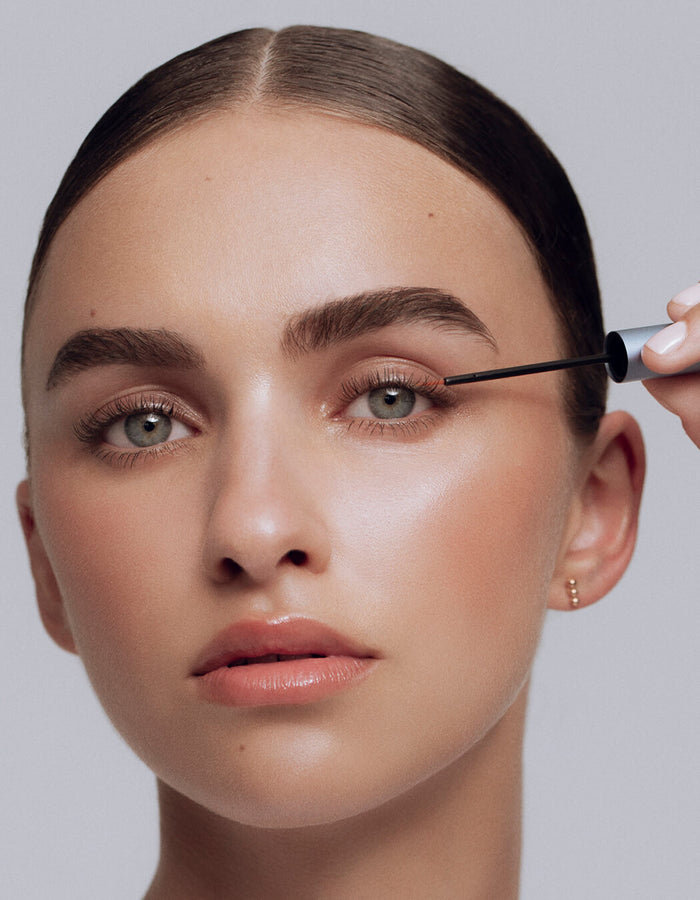 Frau trägt RevitaLash® Advanced Eyelash Conditioner auf ihren Wimpernkranz; Nahaufnahme ihres Gesichts mit glattem, natürlichem Make-up.