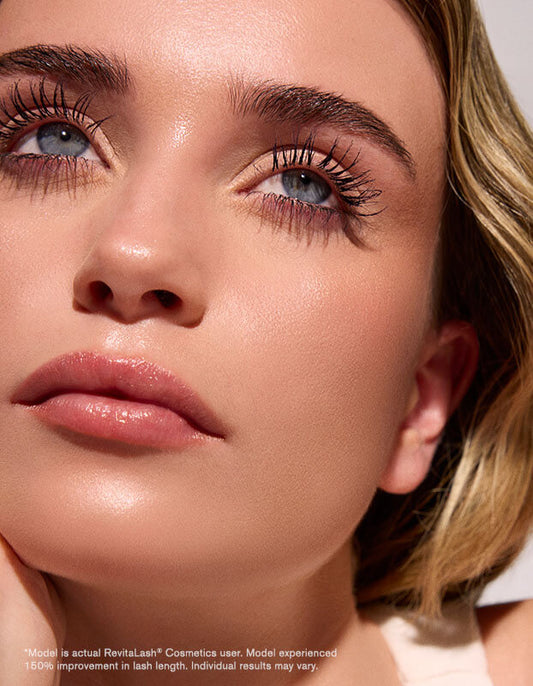 Eine Frau mit langen Wimpern, die durch RevitaLash® Cosmetics Length Define Tubing Mascara betont wurden, blickt nach oben.