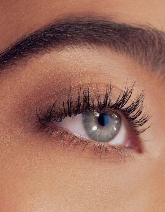 Nahaufnahme eines blaugrauen Auges mit langen Wimpern, geformt mit dem Signature Eyelash Curler von RevitaLash® Cosmetics.
