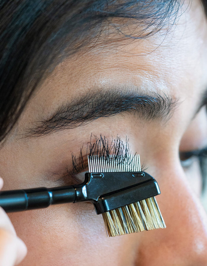 Eine Person benutzt den RevitaLash® Cosmetics Lash & Brow Styler, ein doppelseitiges Bürsten- und Kammwerkzeug, um ihre Wimpern zu pflegen.