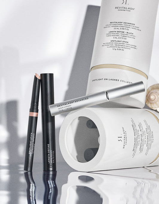 Die Spotlight on Lashes RevitaLash® Advanced Spring Collection 2026 von RevitaLash® Cosmetics besteht aus eleganten Stäbchen, Stiften und Tuben, die auf einer weißen Oberfläche mit sanften Schattierungen angeordnet sind.